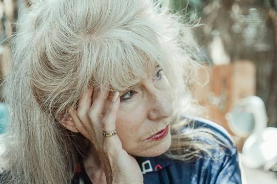 an elder woman resting her face on her hand while facing away